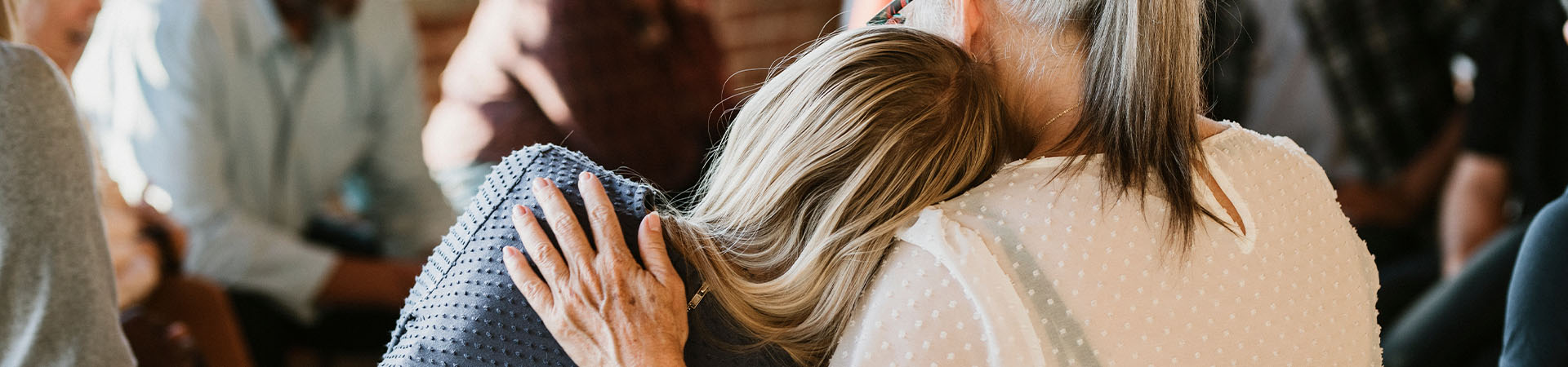 Young woman leaning on older woman in a group setting