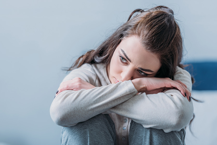 a sad looking young woman hugging her knees